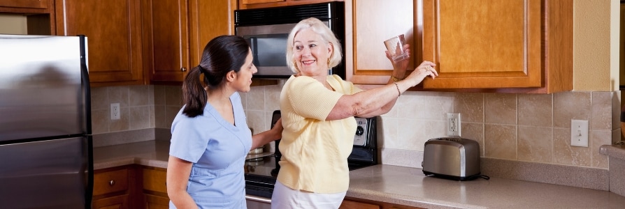 A home health aide helping a patient at home.