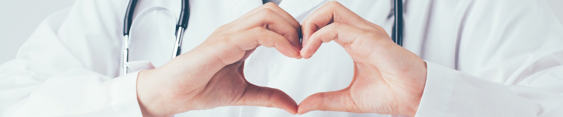 A doctor making the shape of a heart with their hands.