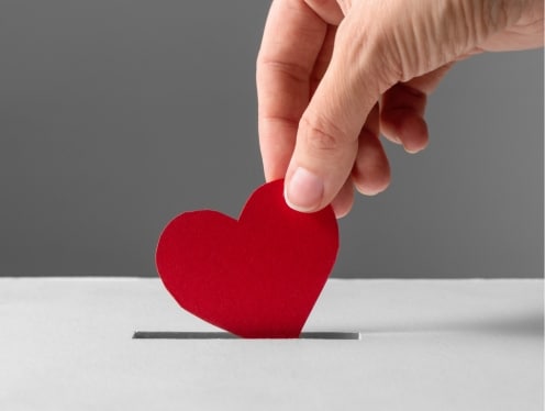 Someone putting a heart into a donation box.